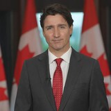Justin Trudeau nasa likod niya ang mga bandila ng Canada.