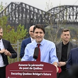 Justin Trudeau en conférence de presse avec le pont de Québec en arrière plan.