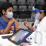 Ten-year-old Rayyan Aziz Rafat receives his COVID-19 vaccine shot from Toronto Public Health's San Basak at a children's vaccine clinic at the Scotiabank Arena in Toronto. 
