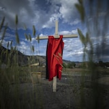 Une robe rouge suspendue sur une croix à la suite de la découverte des sépultures non marquées près de l'ancien pensionnat pour Autochtones, de Kamloops, en Colombie-Britannique, en mai 2021.
