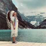 La cheffe contestée de la Première Nation crie Peter Ballantyne, en Saskatchewan, debout sur un quai, devant un lac et des montagnes enneigées. 