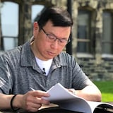 Former Conservative MP Kenny Chiu reads through former governor general David Johnston's first report on election interference. Chiu said he is "disappointed" Johnston didn't recommend a public inquiry. (Ashley Burke/CBC)