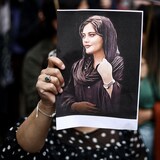 Una persona sostiene un retrato de Mahsa Amini.