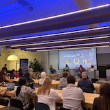 نساء يتحدثن أمام جمهور جالس على كراسي.