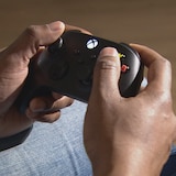 Un homme manipule une manette de Xbox noire.