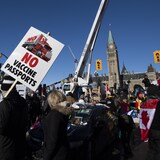 Les gens tiennent des pancartes et agitent des drapeaux le long de la rue Wellington devant la colline du Parlement alors que la protestation contre les restrictions liées à la COVID-19 qui a paralysé le centre-ville d'Ottawa se poursuit.