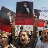 Mujeres protestan mostrando pancartas con el retrato de Mahsa Amini.