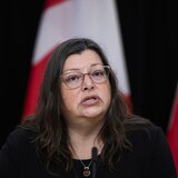 Une femme donne une allocution devant des drapeaux du Canada durant une conférence de presse, à Ottawa, le 27 novembre 2023.