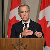 Le premier ministre canadien Mark Carney devant des drapeaux canadiens en point de presse. 