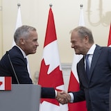 Prime Minister Mark Carney and Polish Prime Minister Donald Tusk shake hands after taking part in a joint news conference at the Chancellery of the Prime Minister in Warsaw on Monday. 
