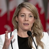 Mme Joly parle au micro devant des drapeaux du Canada.