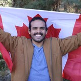 Un homme latino tient un drapeau canadien