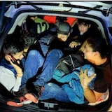 A group of people piled in the back of a vehicle.