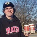 Michael Wallace avec des cafés à la main devant un Tim Hortons.