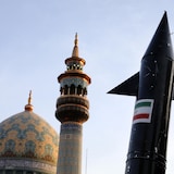 Une vue en contre-plongée montre la tête d'un missile, le dôme d'une mosquée et l'extrémité supérieure d'un minaret.
