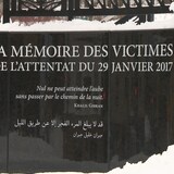 Plan rapproché du monument à la mémoire des victimes de l’attentat du 29 janvier 2017 en hiver. On peut y lire une citation de Khalil Gibran en français et en arabe qui se lit comme suit : «Nul ne peut atteindre l’aube sans passer par le chemin de la nuit».