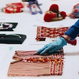 Un.a técnico.a examina textiles antiguos con guantes azules.
Un.e technicien.ne examine des textiles anciens avec des gants bleus.