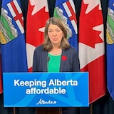 La première ministre de l'alberta, Danielle Smith, parle devant un pupitre, entourée de deux des ministres de son gouvernement, le 1er novembre 2023 à l'Assemblée législative de l'Alberta.