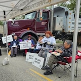 Des manifestants de la Première Nation Splatsin assis devant un camion de construction.