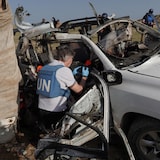 Un inspector de la ONU toma fotos de los restos de un coche.