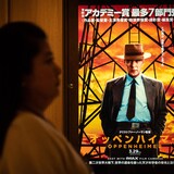 A woman walks past a poster of the film "Oppenheimer" in Tokyo on March 29, 2024.
