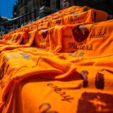 Nasa hagdan sa tapat ng building ang mga orange na t-shirt na nagsasabing every child matters. 