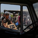 A Palestinian carries a box containing food and humanitarian aid.