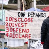 A man reads a sign of demands posted outside a pro-Palestinian encampment set up on McGill University's campus in Montreal on Tuesday. 