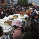 Une foule entourant des cercueils 