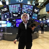 Peter Tuchman, clipboard in hand, looking at various screens on the floor of the New York Stock Exchange.