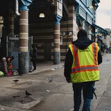 Un travailleur de rue marche en direction d'une station de métro. Des dizaines de sans-abri et de consommateurs de drogue sont installés dans la rue.