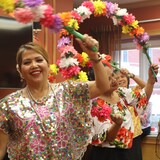Mga kababaihan na nagsasayaw hawak ang maliliit na arko na gawa sa bulaklak.