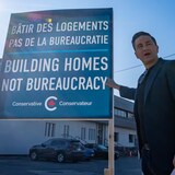 Pierre Poilievre nakaturo sa isang sign na nagsasabing 'Building homes not bureaucracy.'