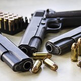 Trois pistolets déposés sur une table avec des balles. 