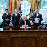 Five men are behind a desk with a map of Alaska. 