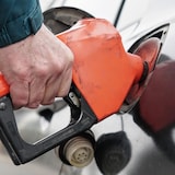 
A hand holds a gas gun pouring fuel into a car in Calgary on May 4, 2022.