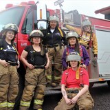 Un groupe de femmes devant un camion de pompiers.