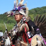 Indígena canadiense con un traje tradicional decorado con plumas.