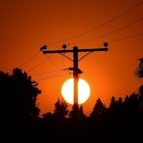 The sun sets behind power lines.