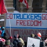 People wave flags and hold signs as a truck convoy protesting COVID-19 mandates makes its way through downtown Ottawa on Jan. 28, 2022. The federal government is already preparing for another convoy protest planned for next Feburary. (Ivanoh Demers/Radio-Canada)