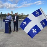 Un militant agite un petit drapeau du Québec alors que Paul St-Pierre Plamondon et un de ses candidats offrent un point de presse.