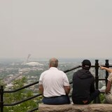 A group of tourists look east from a lookout on Mount Royal on Monday. A smog warning is in effect for Montreal and multiple regions of the province due to forest fires.