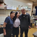 A young woman with her elderly parents in a restaurant kitchen.
