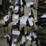 Various handguns and other types of firearms tagged by the RCMP are displayed on a concrete floor.