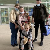 Un petit garçon dans un pousse-pousse, en compagnie de trois adultes, deux femmes et un homme, à l'aéroport de Winnipeg le 23 mai 2022. 