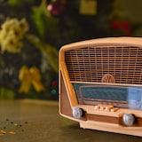 Une ancienne radio repose sur une table de bois devant un sapin de Noël.