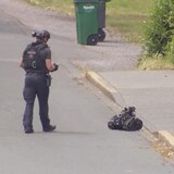 Un policier tient une télécommande avec laquelle il guide un petit robot.