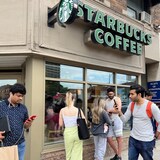 People crowd around a Toronto Starbucks to use its free wifi on the Bell network Friday morning during a major outage of Rogers Communications' mobile and internet networks that was causing widespread disruptions across Canada.