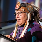 A woman wearing a traditional headdress speaks to the microphone.