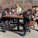 Samiullah Ashna entouré de ses cinq enfants assis sur une table à pique-nique devant un arbuste.